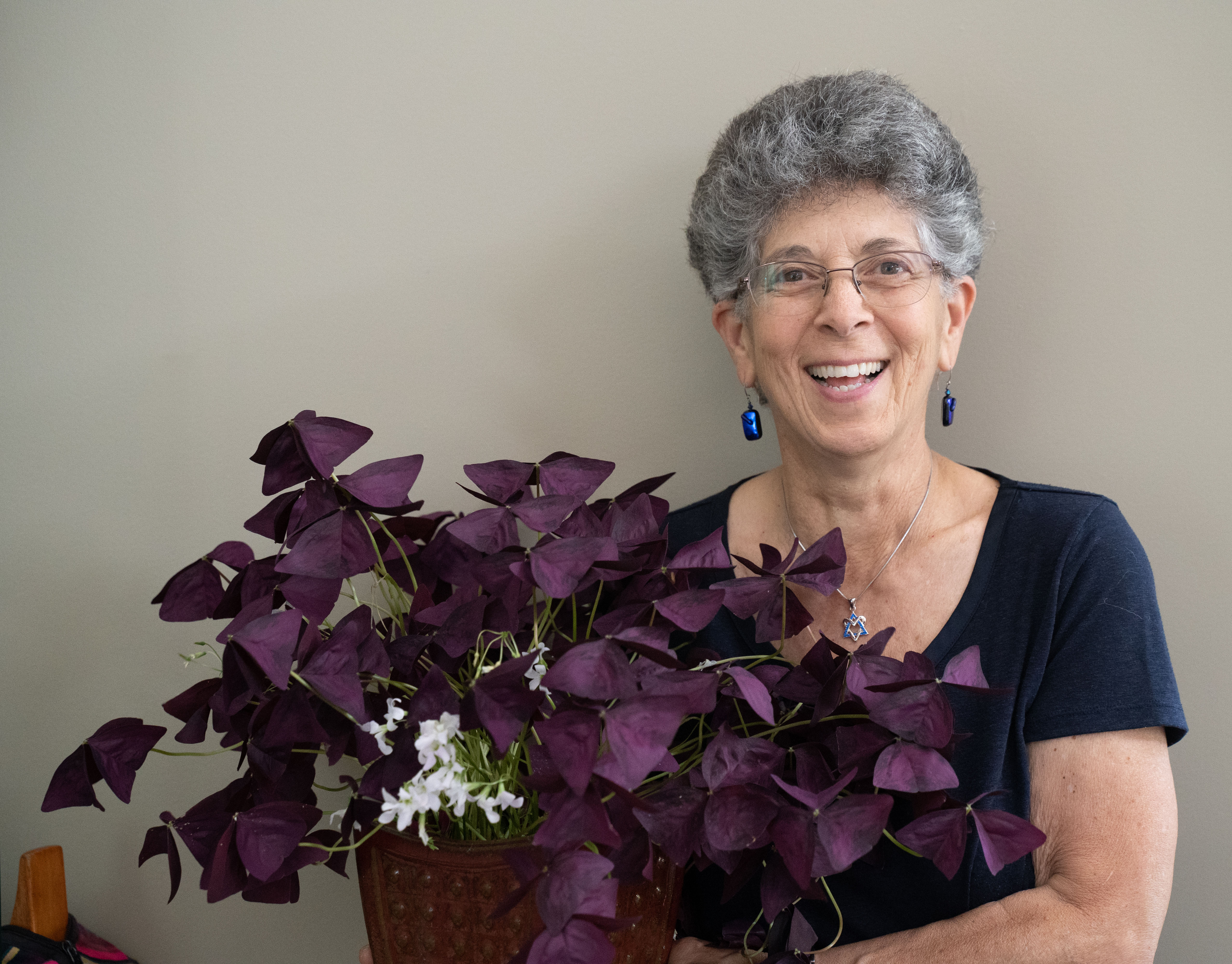 Suri smiling and holding a purple houseplant
